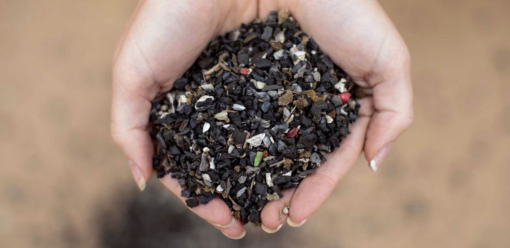 Hands holding auto shredder residue consisting of rubber and other mixed plastics 