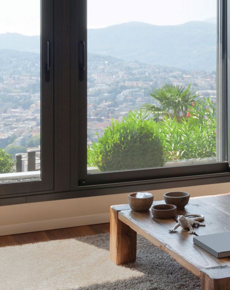 Living room with large windows overlooking hills and a wood coffee table. 