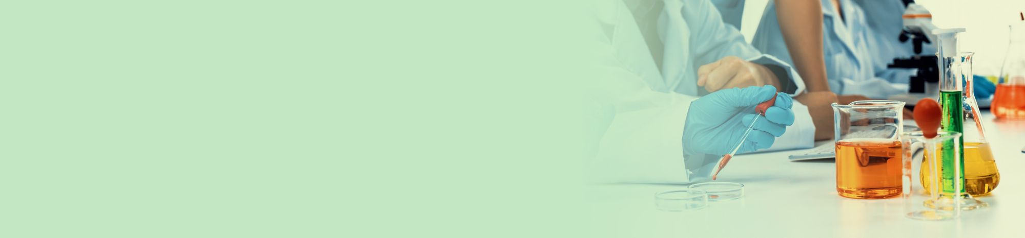 Scientists in lab coats sit near colorful beakers 