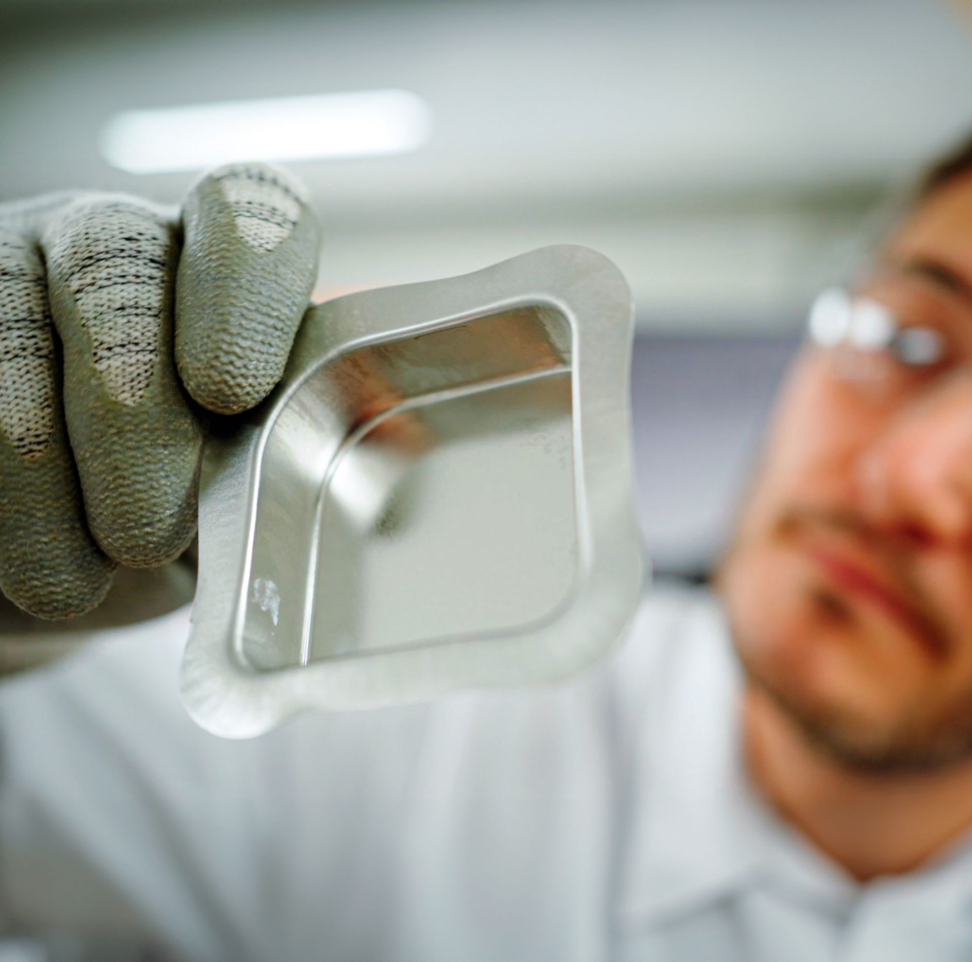 A scientist inspects flexibility and adhesion of coating formulations with an asymmetrical deep drawn box. 