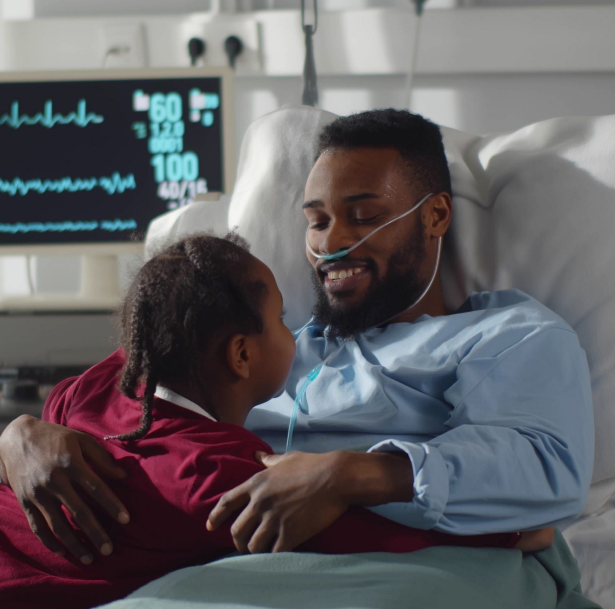 A man in a hospital bed embraces a child. 