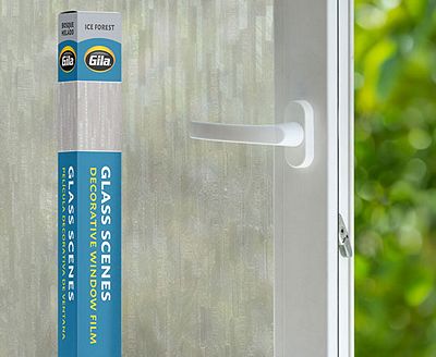 Retail packaging displayed next to a window treated with the Ice Forest decorative film.