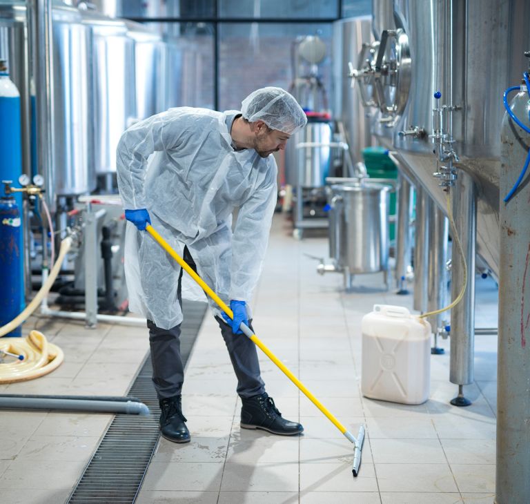 A person cleans floors with an industrial cleaning machine. 