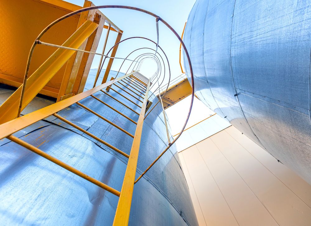 Looking up a ladder from bottom of an industrial tank. 