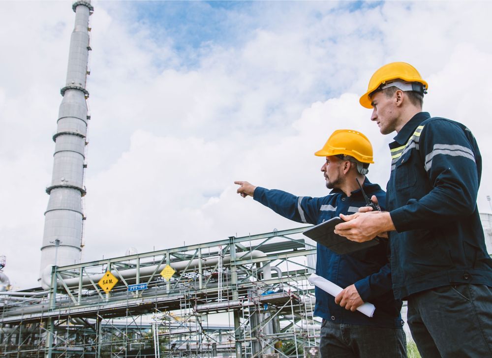 Two men inspect equipment outside a processing facility.  