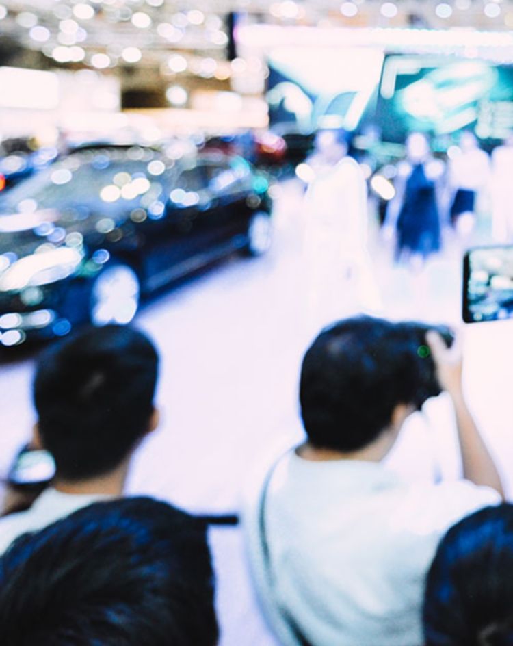 Crowd photographing cars on display at an indoor auto show. 