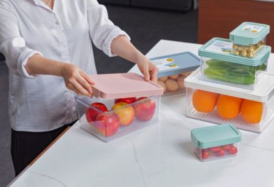 A person closes lids on plastic food storage containers. 