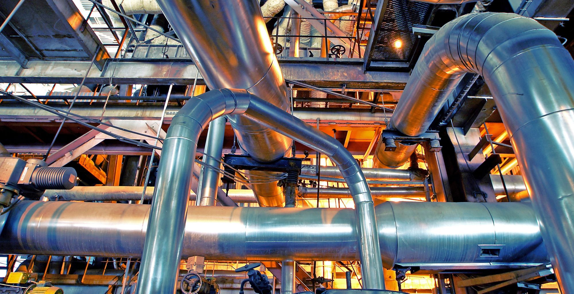 An inside look of an industrial plant with multiple pipes weaving through one another. 