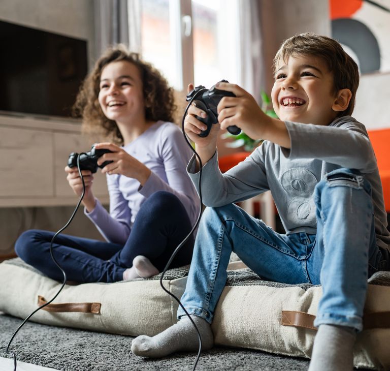 Two smiling kids holding video game controllers. 