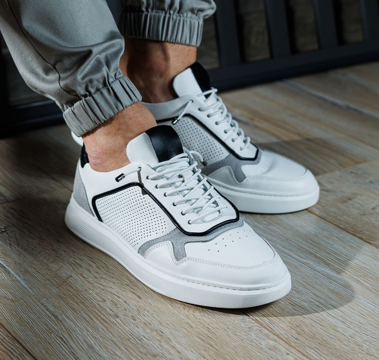 White leather tennis shoes on a person’s feet. 
