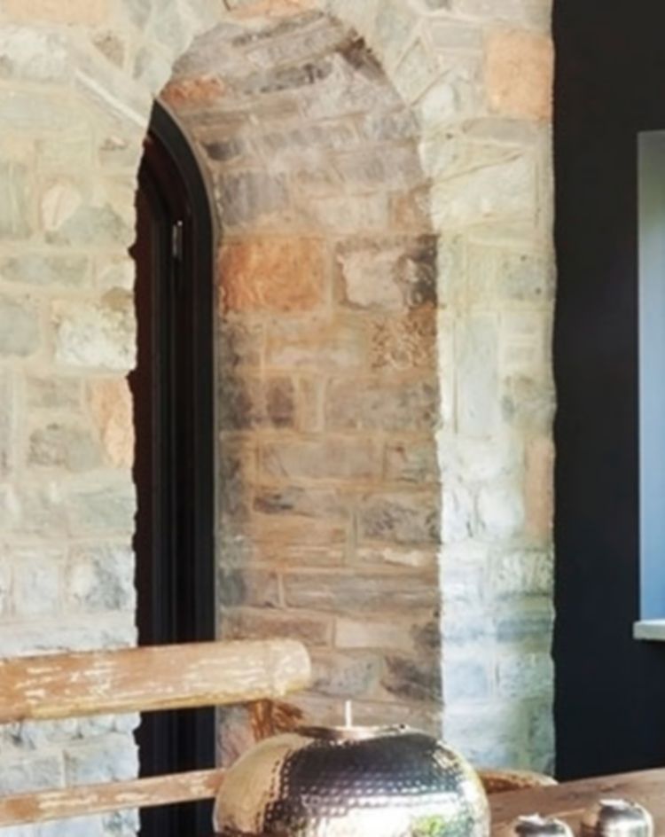 Rustic dining area with stone walls and a wooden table. 