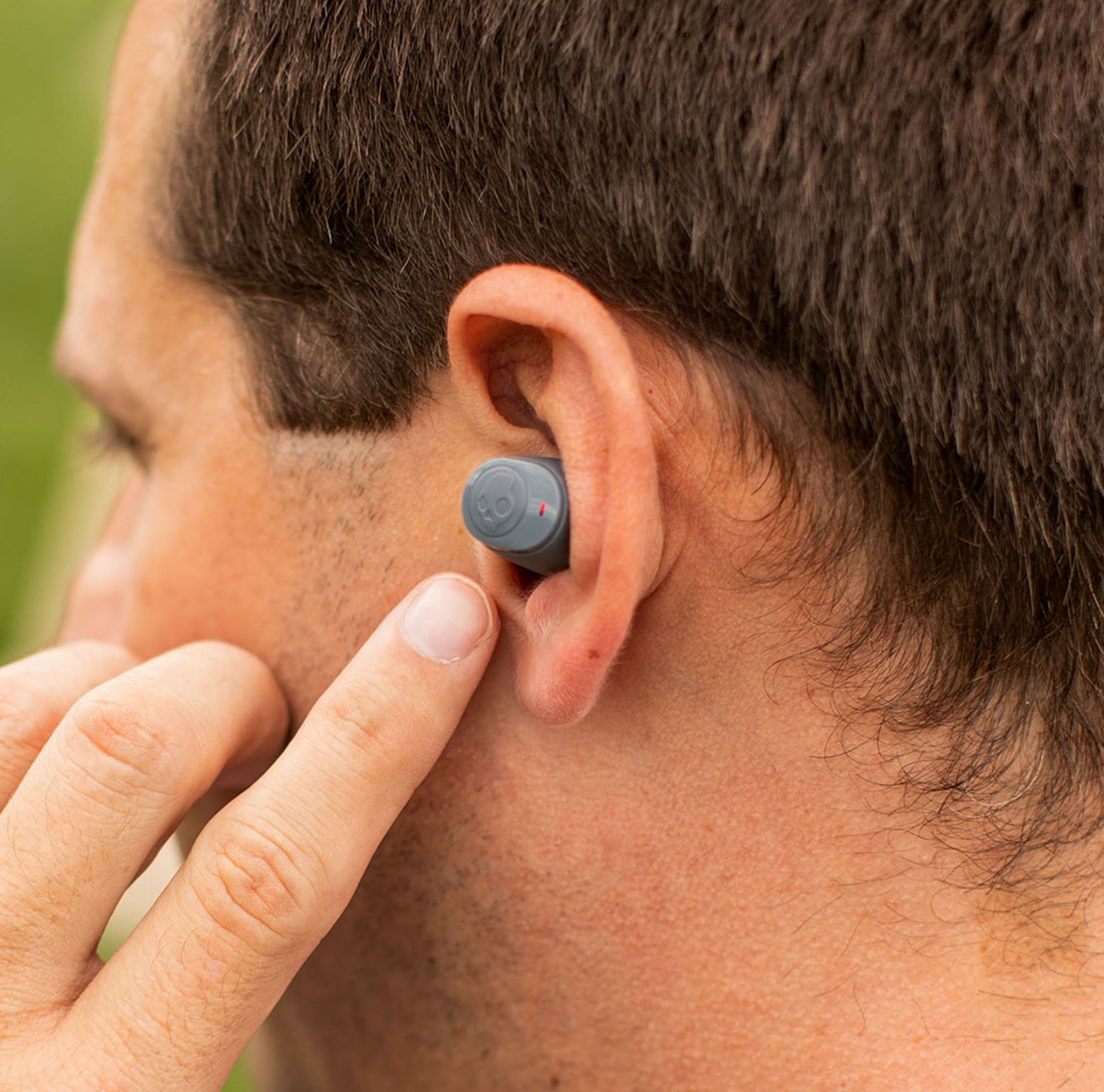 A man adjusts an earbud in his ear. 