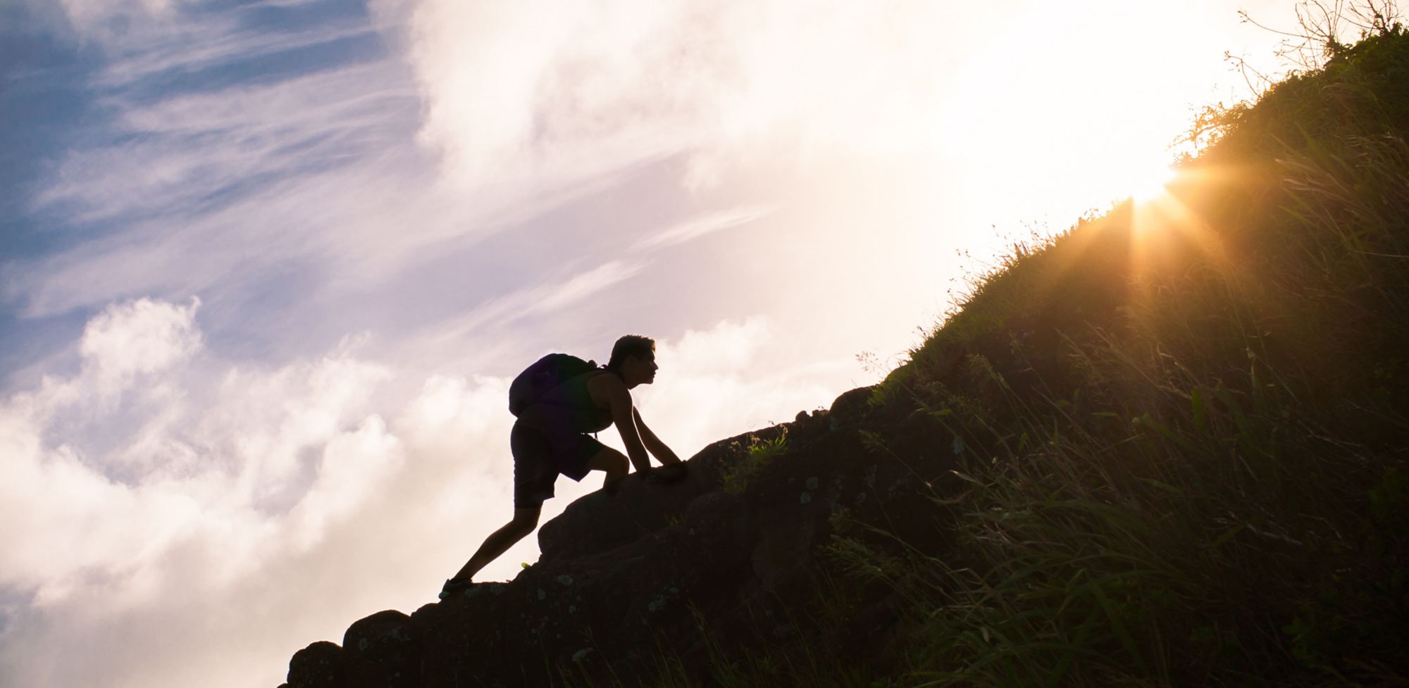 Silhouette d’un homme gravissant une montagne 