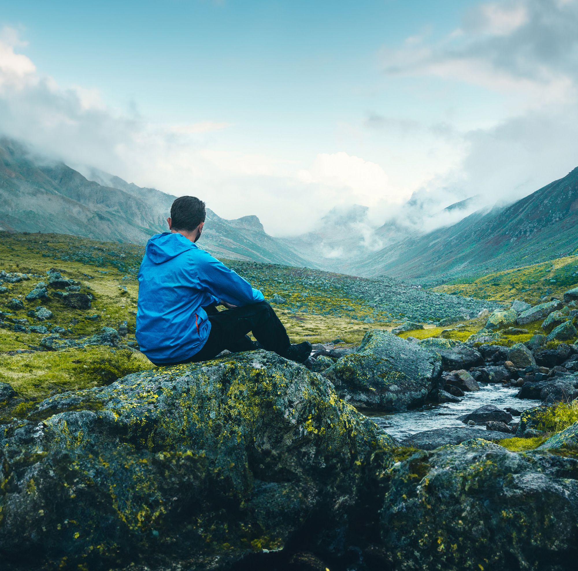 Man sitting on a rock looking at the mountains.