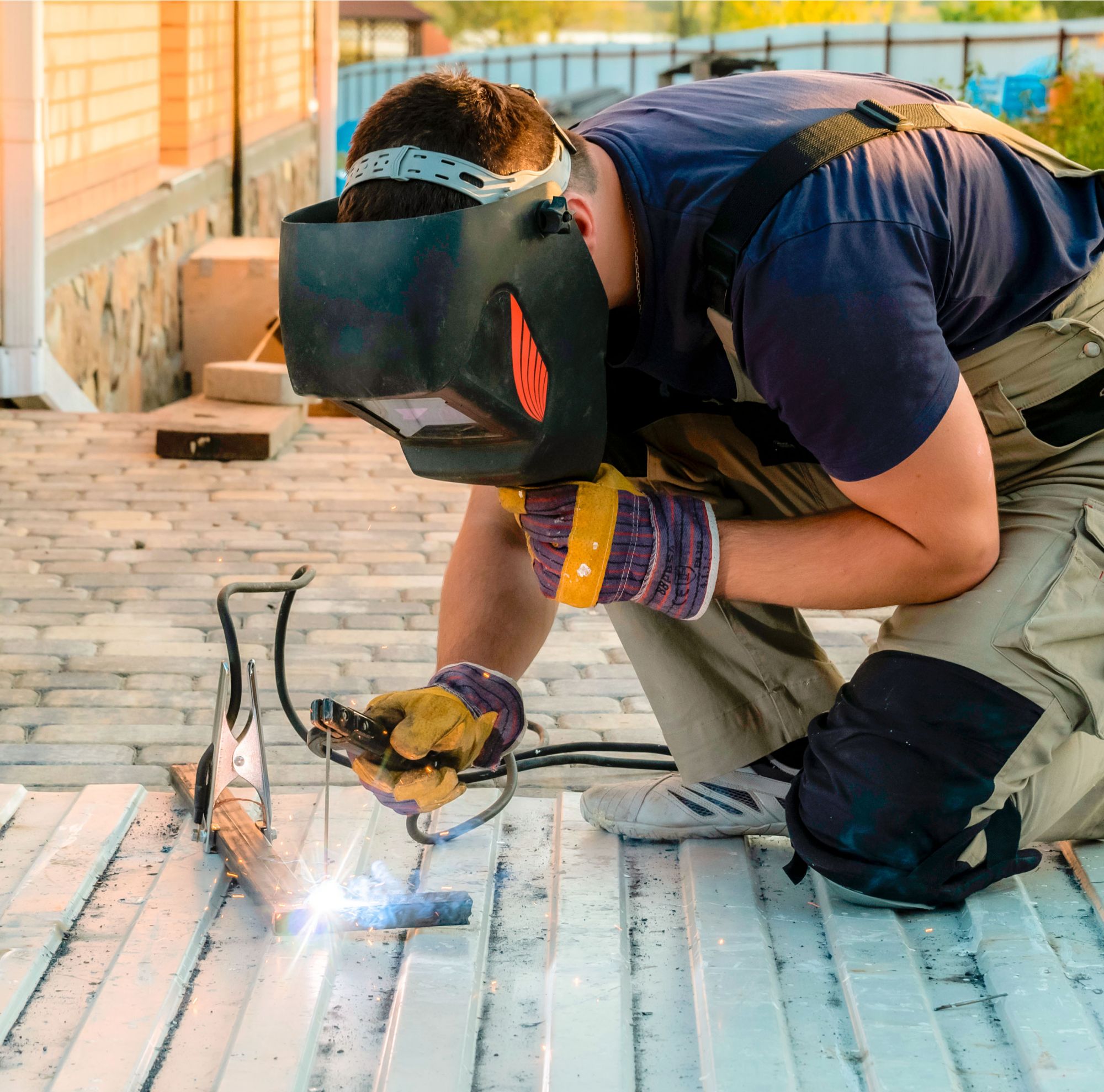 A man welding, holding a welding hood to his face. 