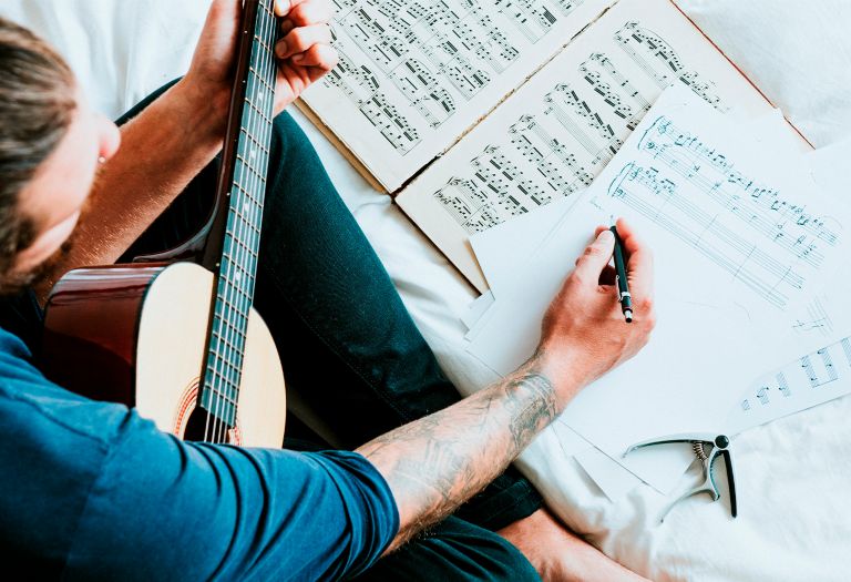 A man with guitar writing music 