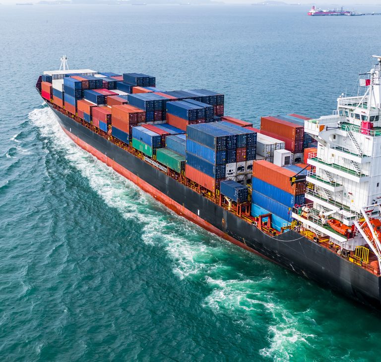 A cargo ship at sea carries shipping containers. 