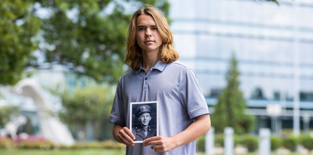 Mark Sago holding a black and white photo of his great-grandfather 