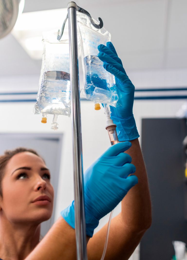 A medical professional replaces an IV bag made with medical polymers. 