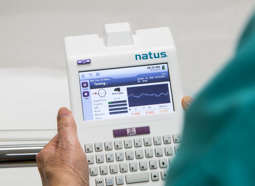 A healthcare provider holds a hearing screening device made of opaque copolyester.  