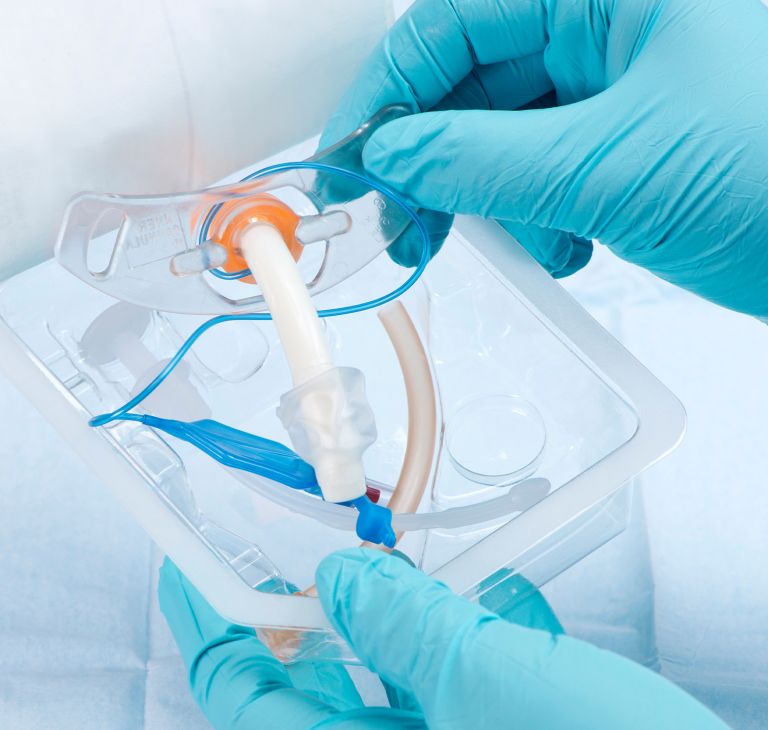 An IV set is removed from medical packaging. 
