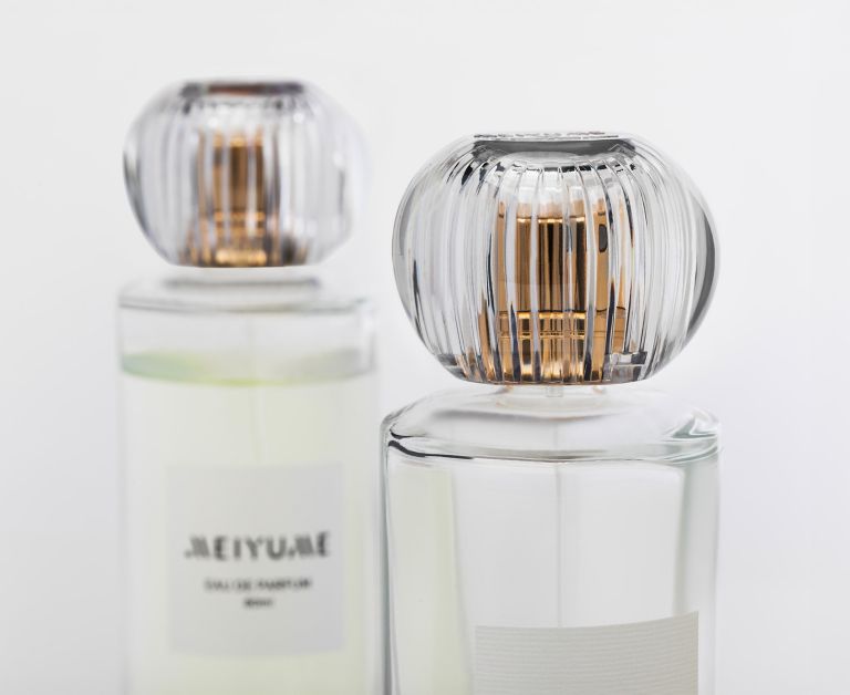 Two perfume bottles topped with clear, crystal halo caps crafted from Eastman Cristal recyclable PET resin.  