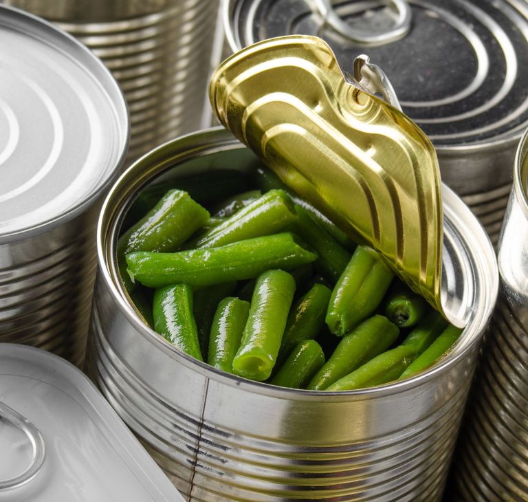 A metal can of green beans is opened from the top. 