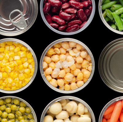 Open cans of fruit and vegetables are shown from above.