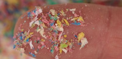 Finger with colorful microplastic particles 