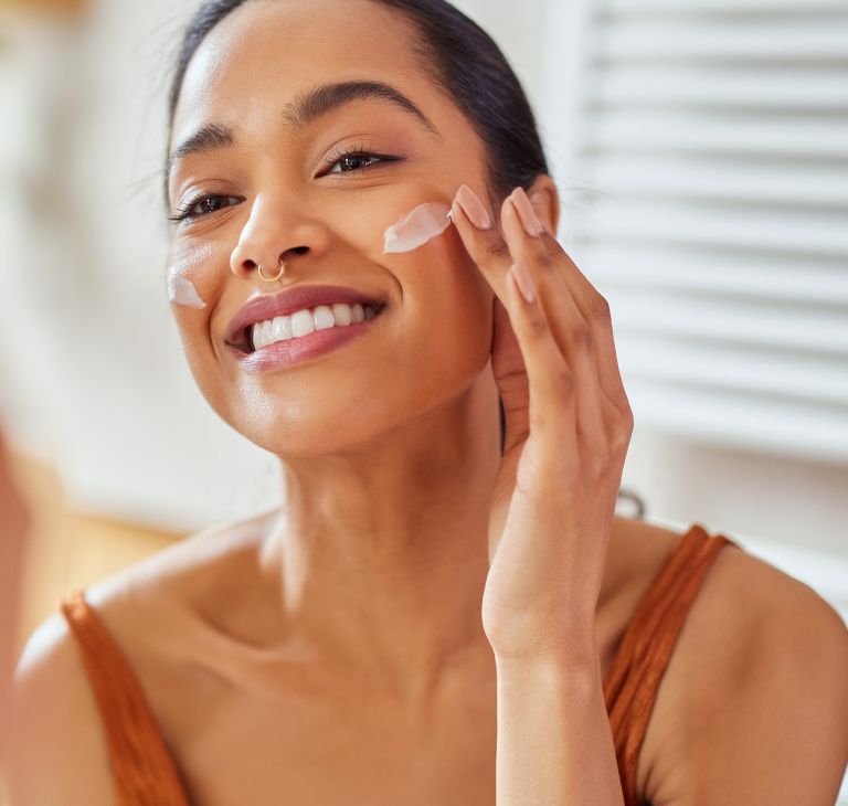 A person applies moisturizer to their face. 