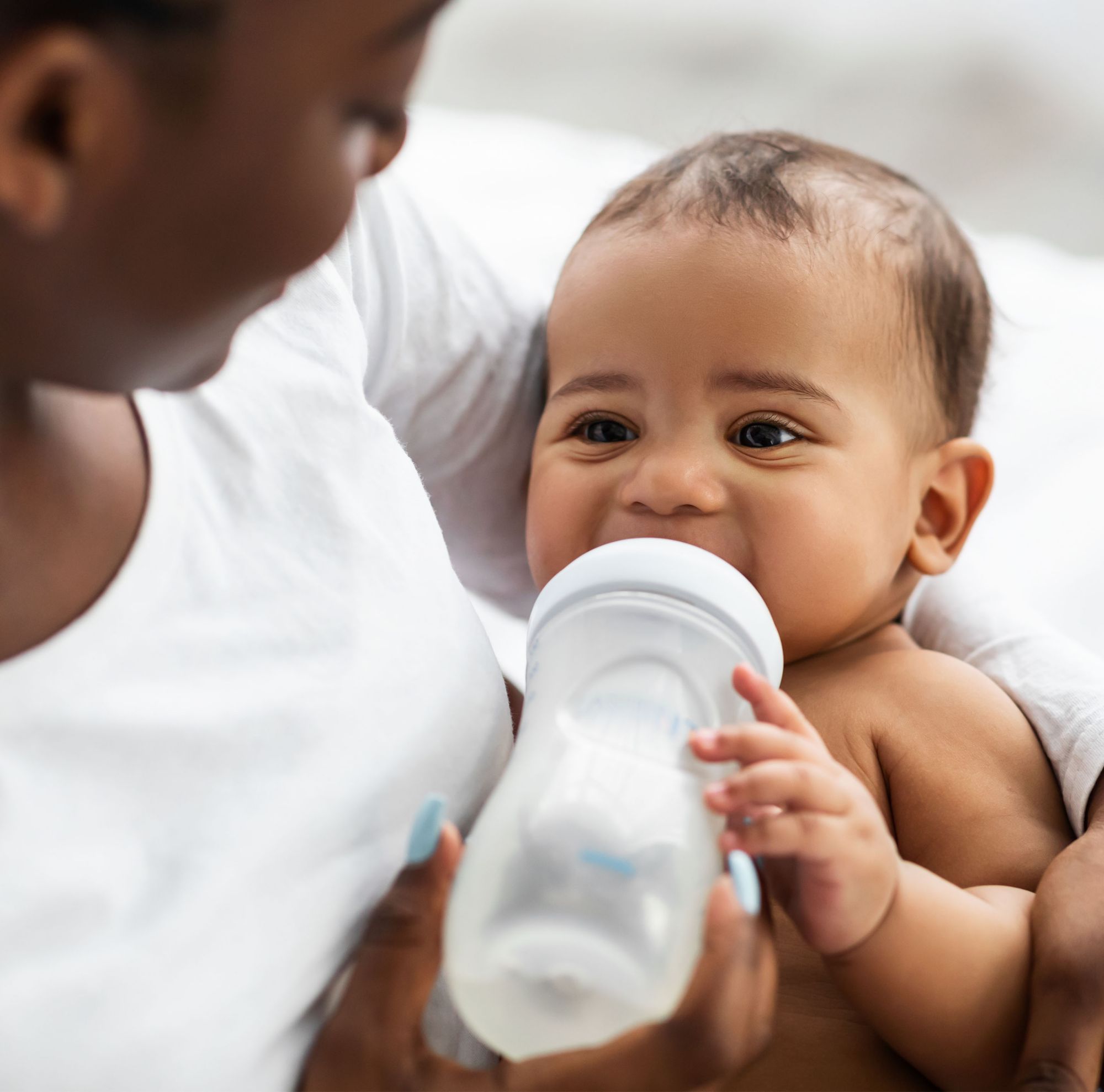 A mother feeding her baby with a baby bottle full of milk.  