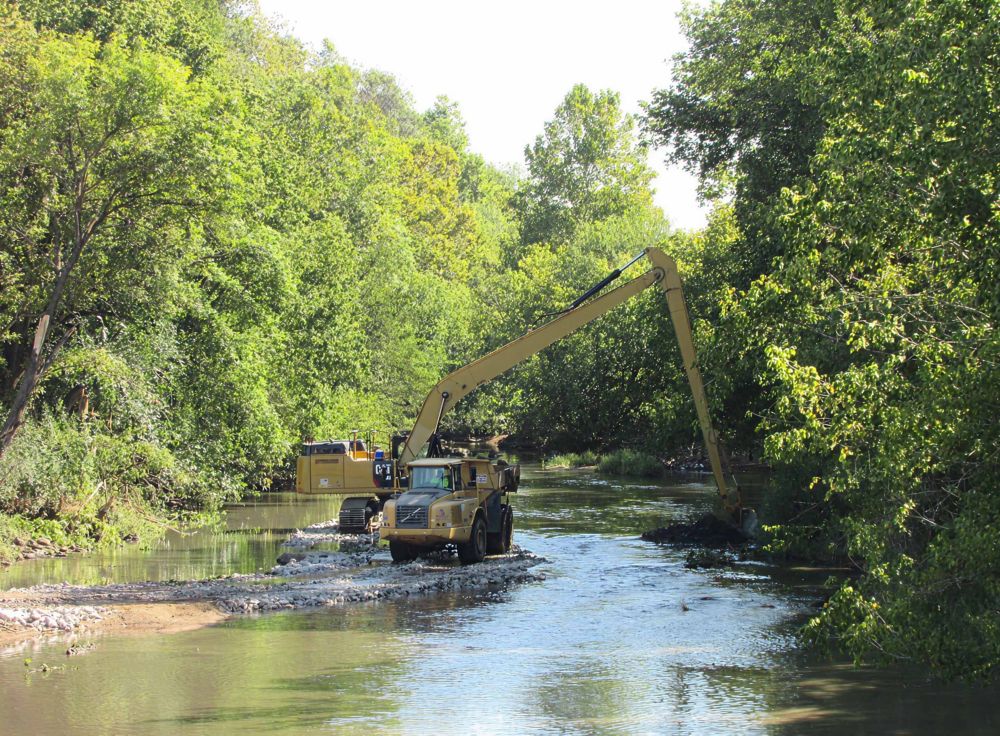 Multiple escavators working on a riverbed. 