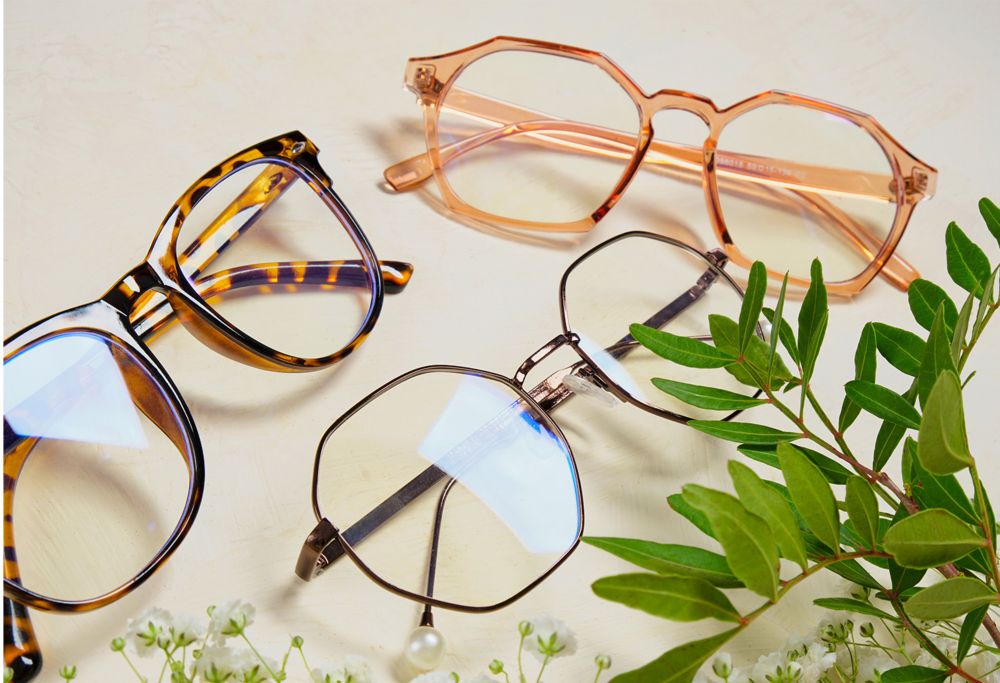 Tortoiseshell glasses, pink-framed geometric glasses and wire-framed glasses on a white surface. 