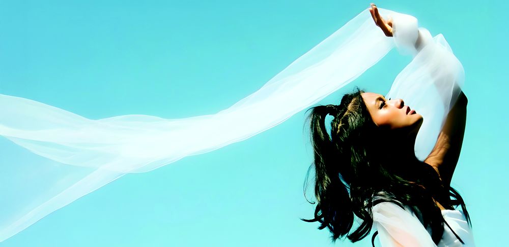 Model holding sheer white fabric made from Naia Lyte, a cellulose acetate filament yarn with enhanced tenacity. 