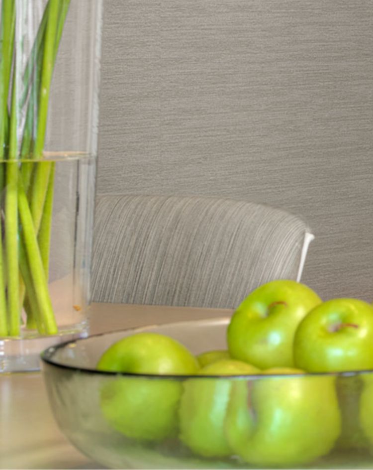 Light-colored meeting area with a bowl of green apples on the table, next to a glass partition featuring a white leaf-patterned privacy film. 