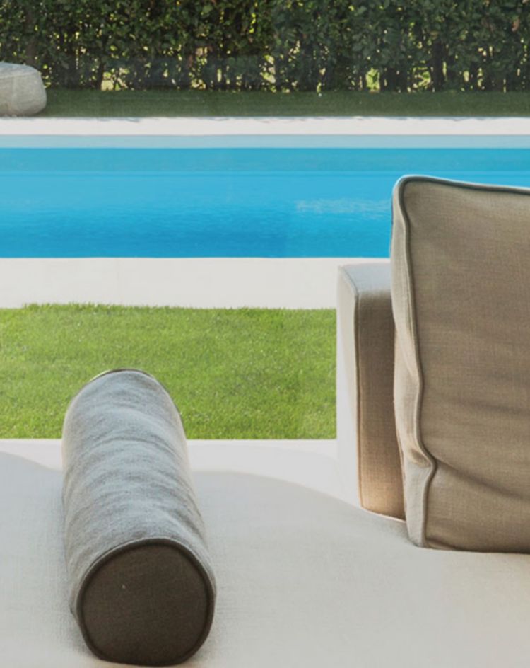 Indoor seating area facing a backyard pool and hedge. 