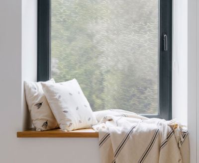 Cozy, private window nook showing the installed Ocean Waves film behind throw pillows.