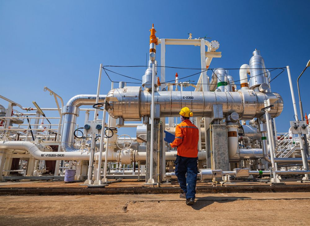 An engineer inspecting oil refinery machinery. 