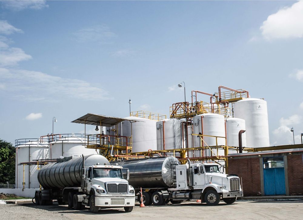 Oil storage trucks sit outside a processing facility.  