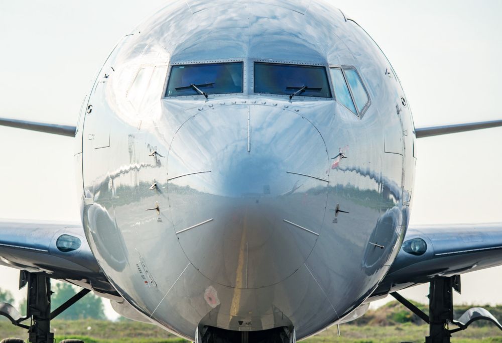 A gray grounded plane is shown from in front of the nose. 