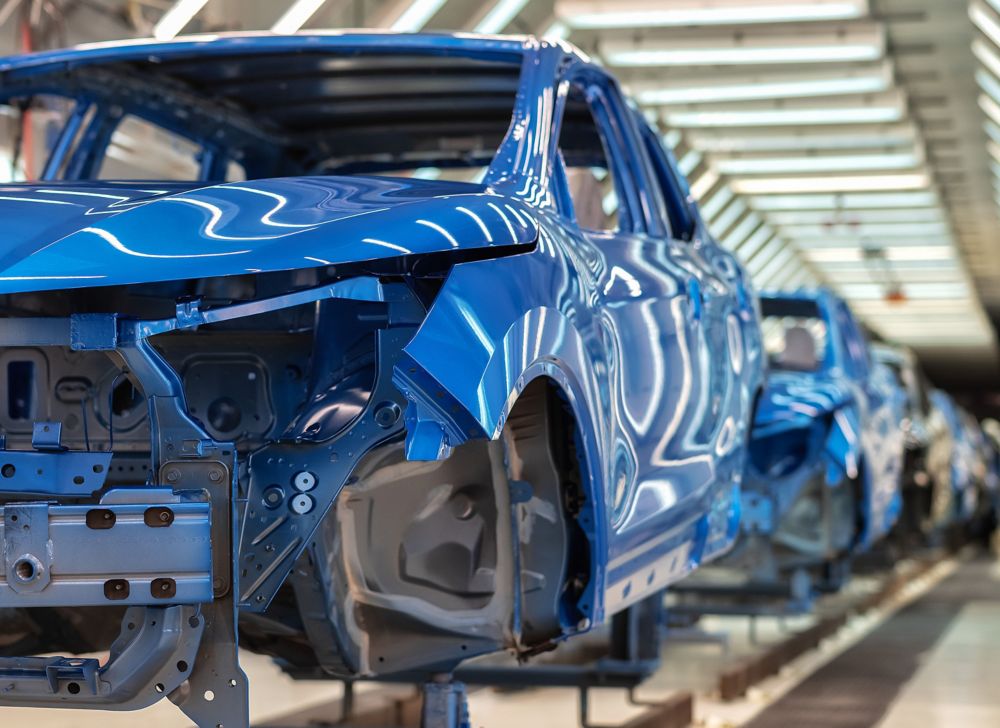 Blue, partially built cars are shown on a production line. 