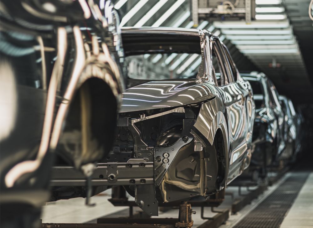 Partially built cars appear on a manufacturing assembly line. 