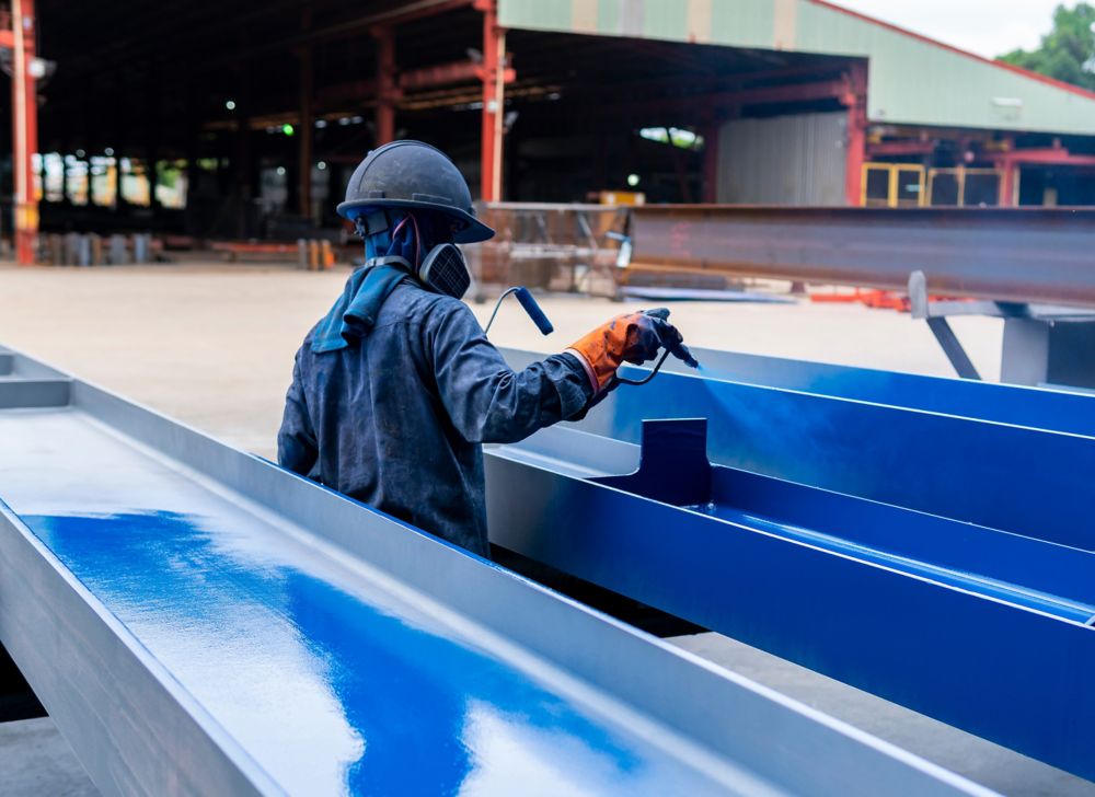 A person coating industrial steel beams 