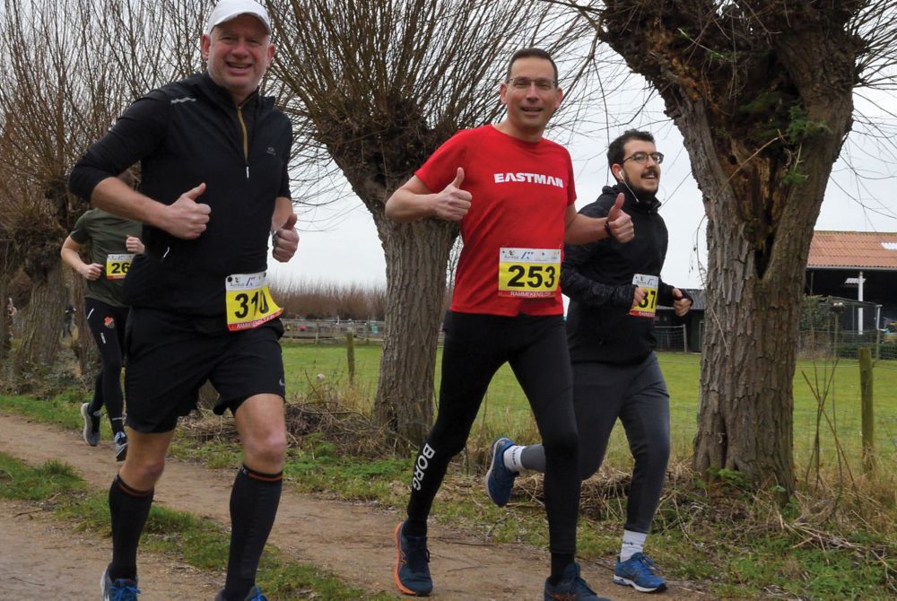 Paul gives the two thumbs up gesture and a smile while running in his Eastman shirt. 