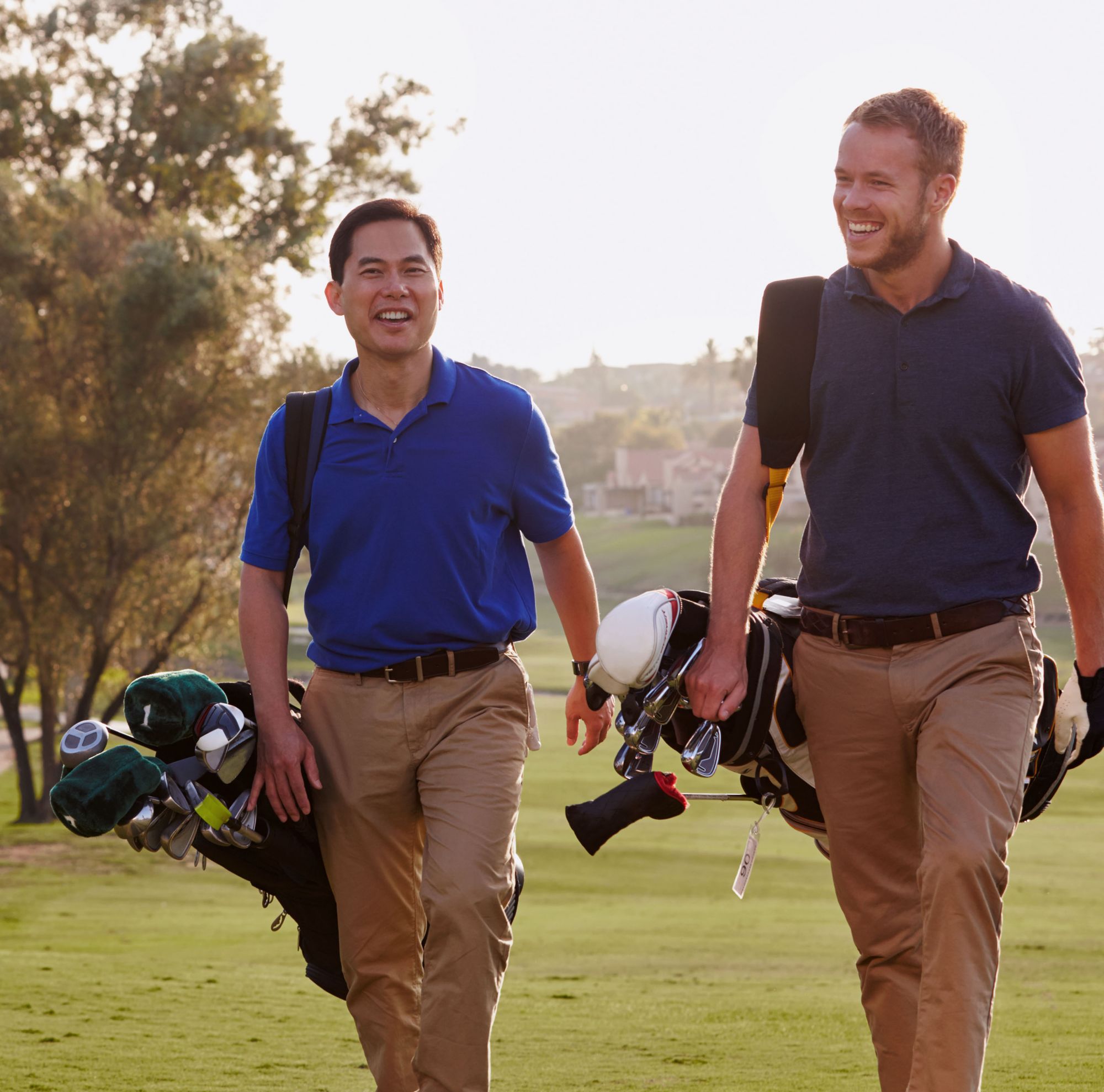 Two men smile while walking on the golf course. 