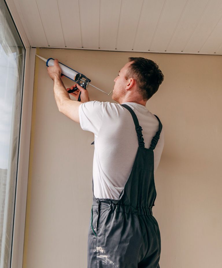 A man applies caulk in the corner of a room. 