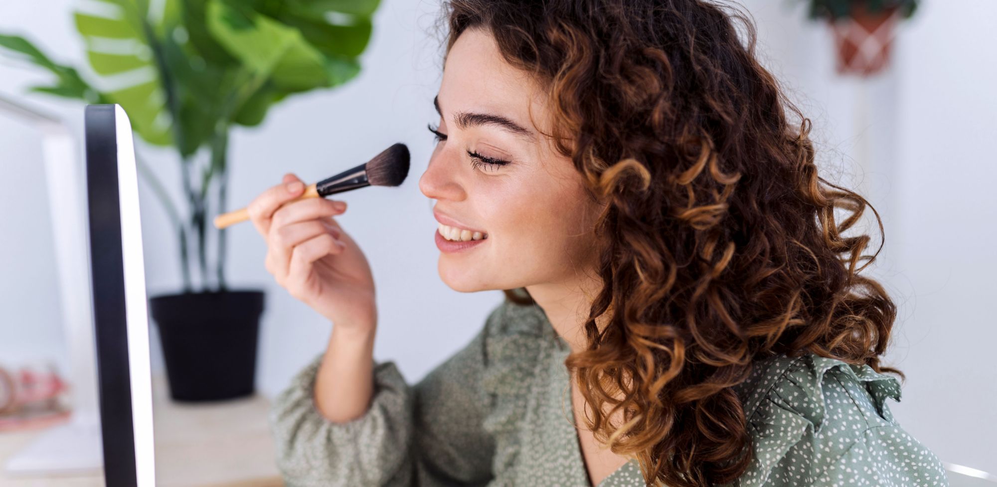 A person applies powder makeup in front of a mirror. 