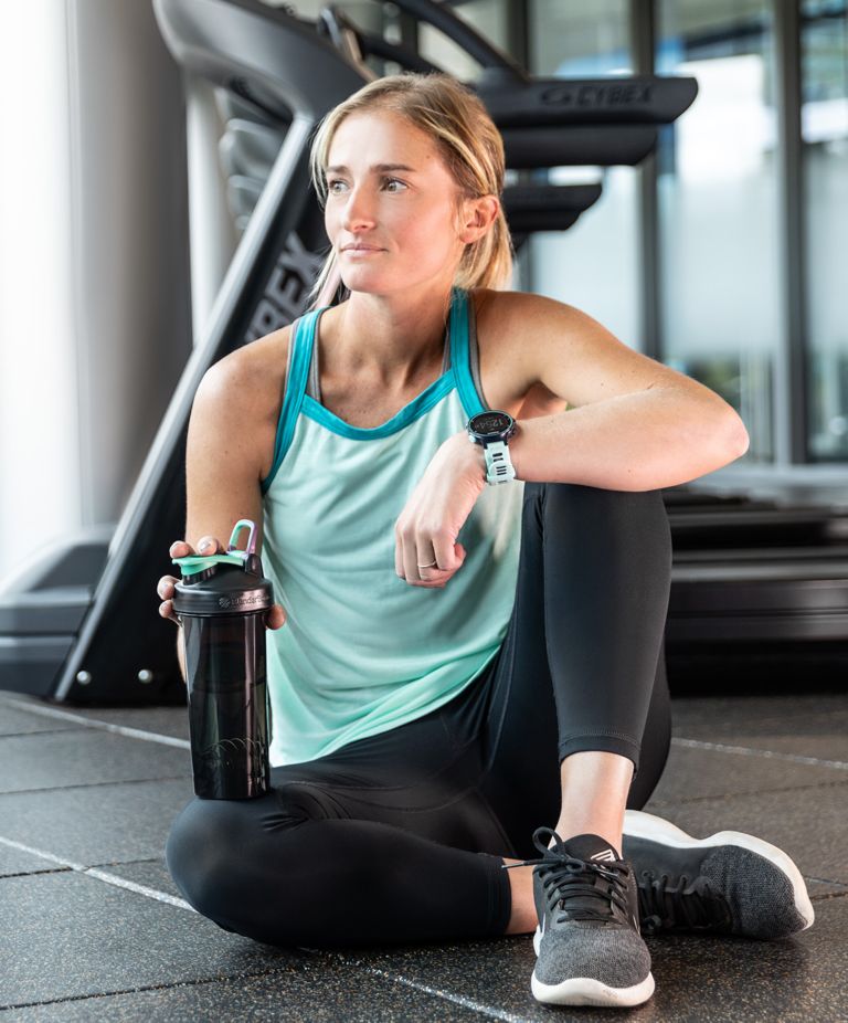 A person smiling as she holds a black shaker bottle. 