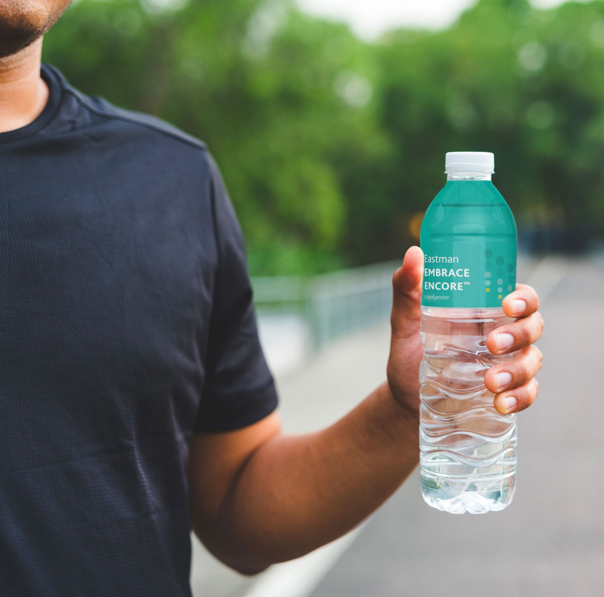 Person holding a water bottle with a Eastman Embrace Encore label. 