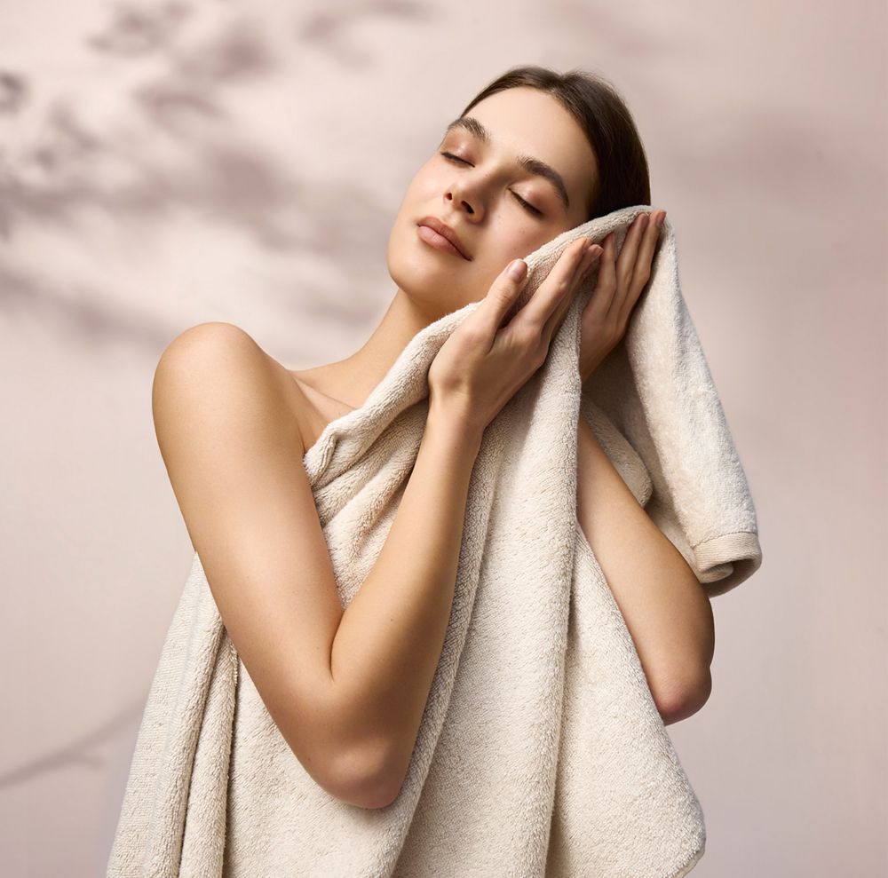 A person holds a white towel to their face. 